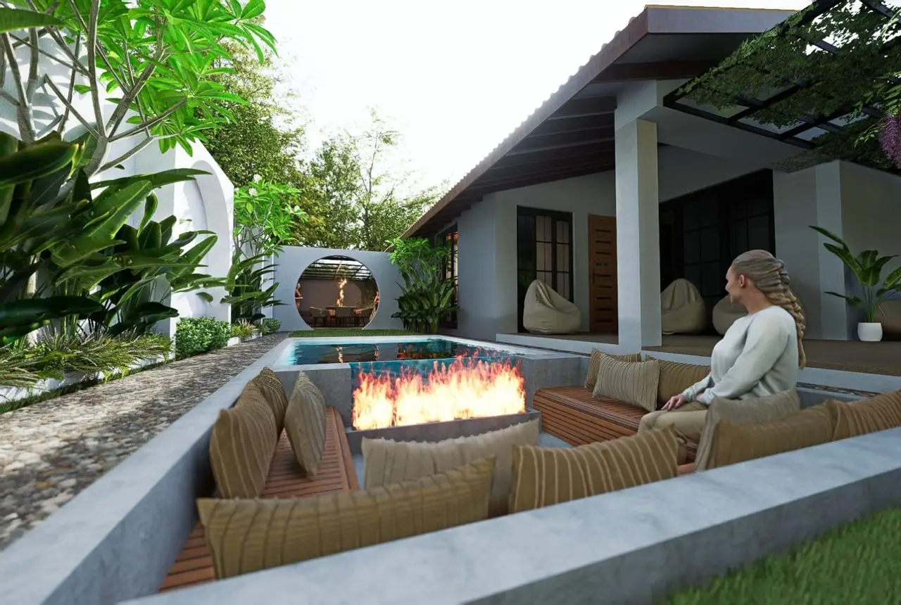 A woman sits by a sunken outdoor fire pit surrounded by cushions, beside a small pool in a modern garden patio, with a contemporary house and lush green plants in the background.renovation